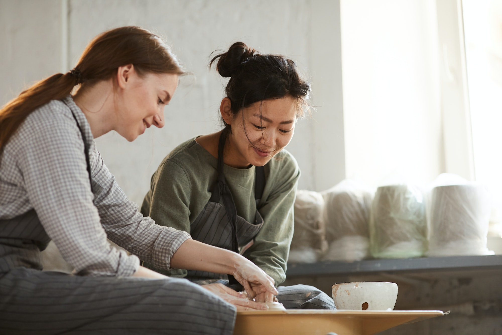 Content multi-ethnic women creating clay pot together