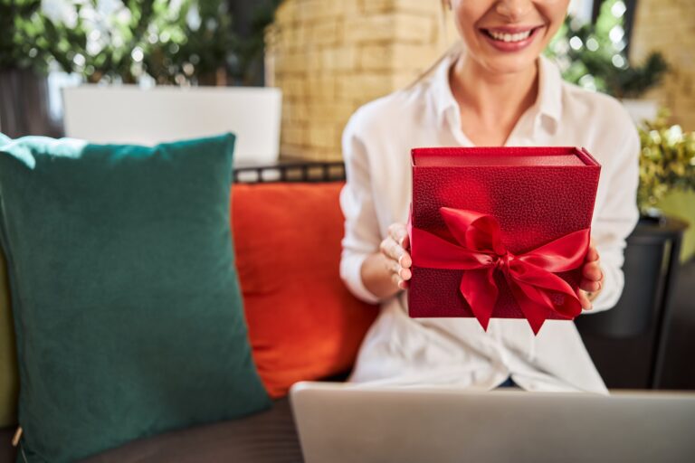 Smiling woman sitting on the sofa with gift in hands