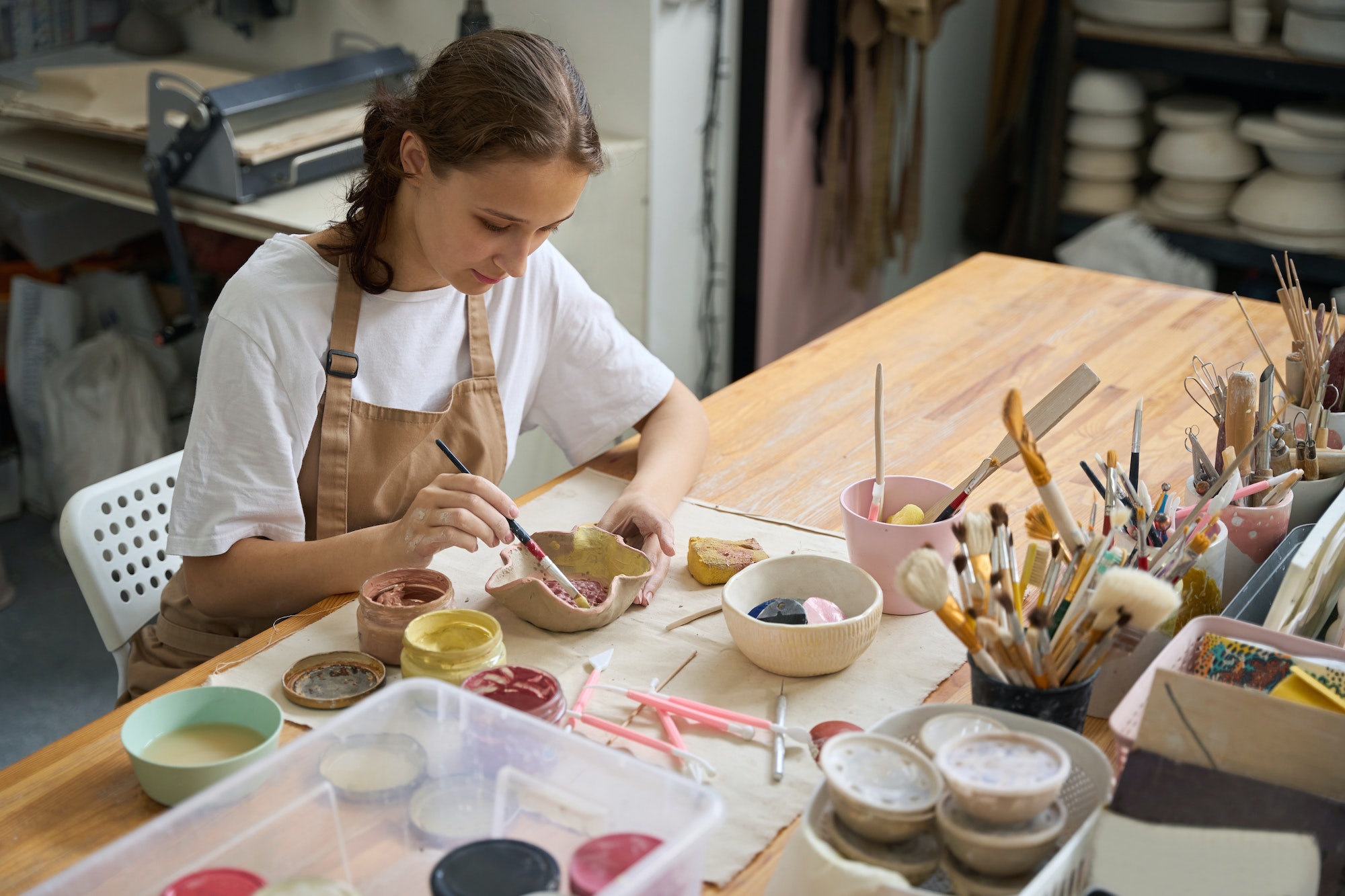 Young woman in an art workshop decorating a clay plate