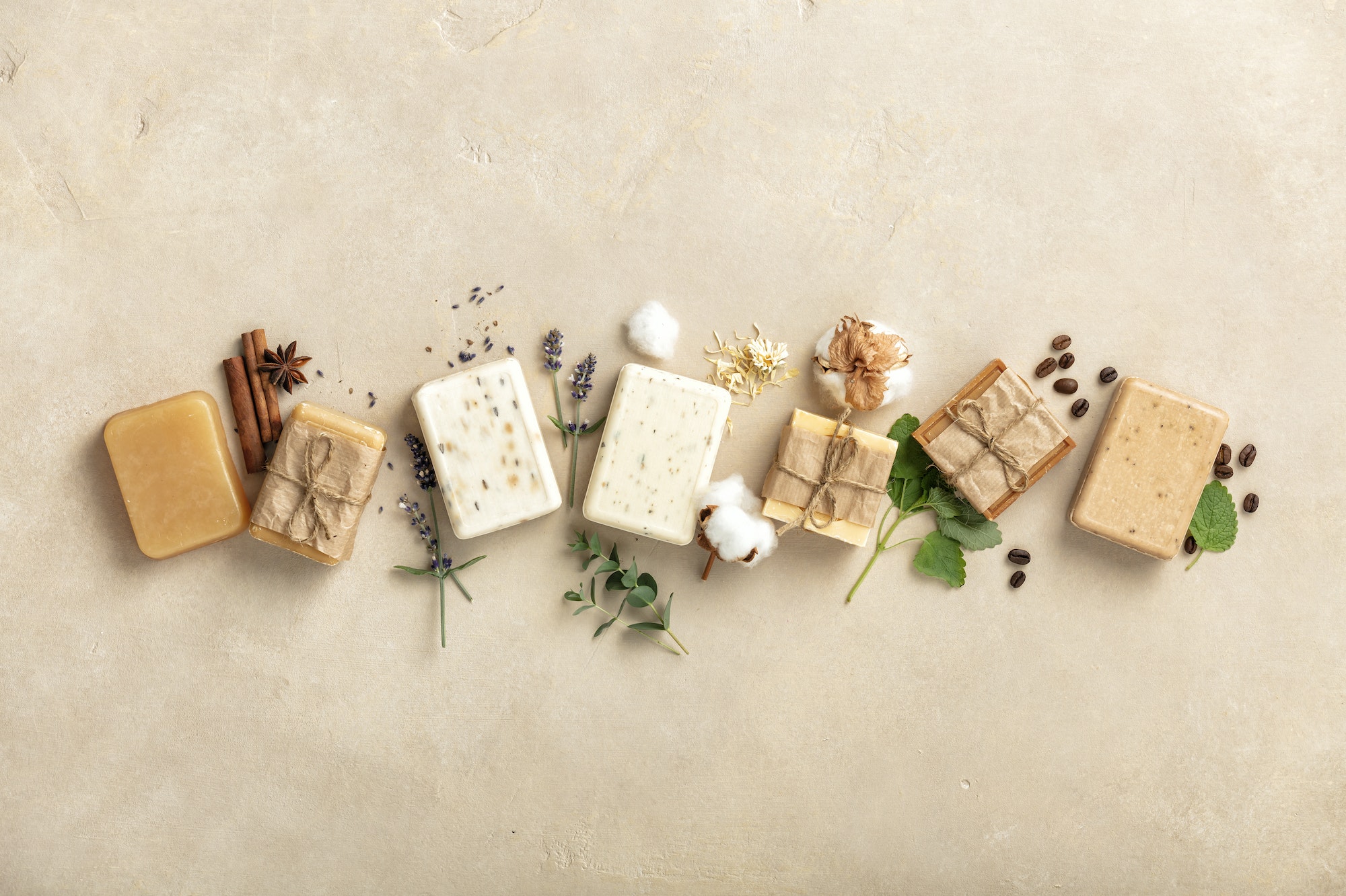 Handmade organic soap bars and ingredients on natural stone background, flat lay