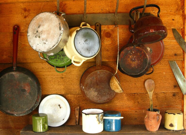 Old frying pans and cooking pots hanging on a wooden wall